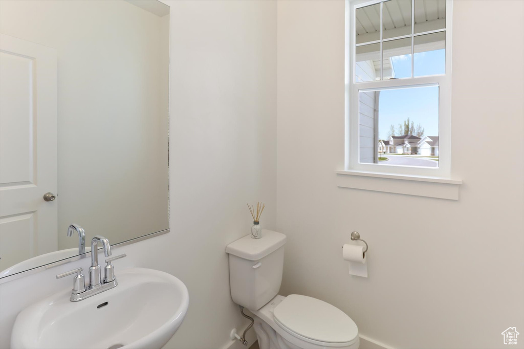 Bathroom featuring toilet, baseboards, and a sink