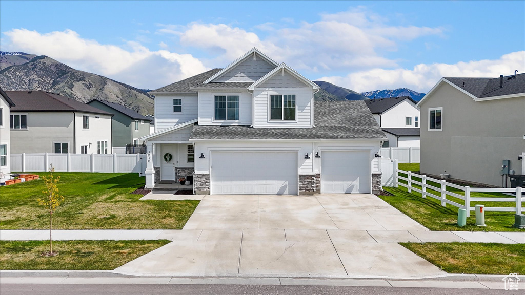 View of front of property with a front yard, fence, concrete driveway, an attached garage, and a shingled roof
