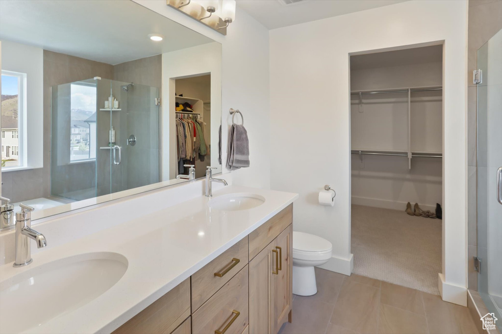 Bathroom featuring a sink, tile patterned flooring, a shower stall, and toilet