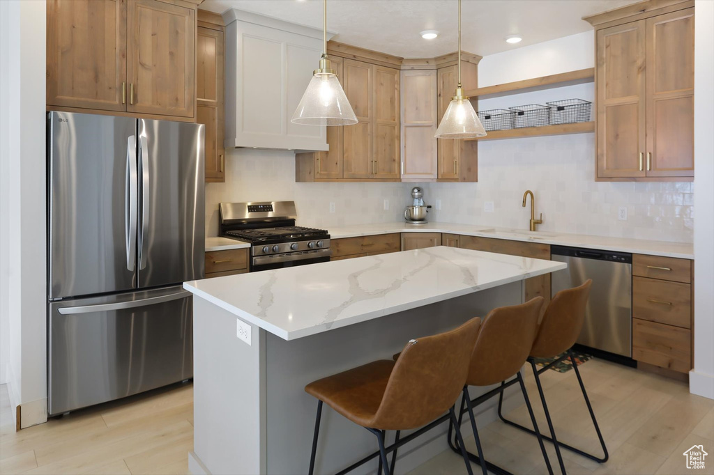 Kitchen with pendant lighting, a breakfast bar, a center island, a sink, and appliances with stainless steel finishes
