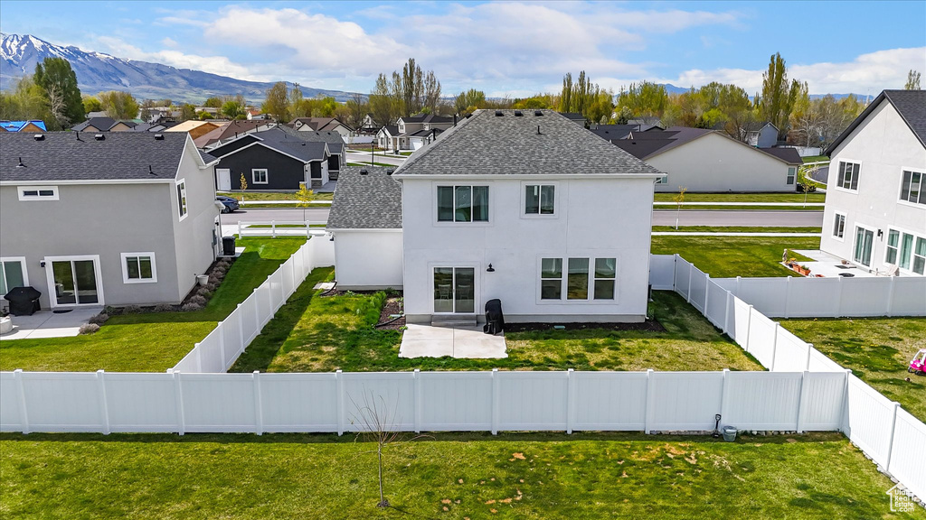 Rear view of property featuring a lawn, stucco siding, and a residential view