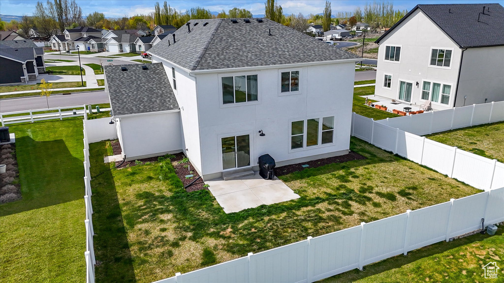 Back of house featuring roof with shingles, stucco siding, a yard, and a residential view