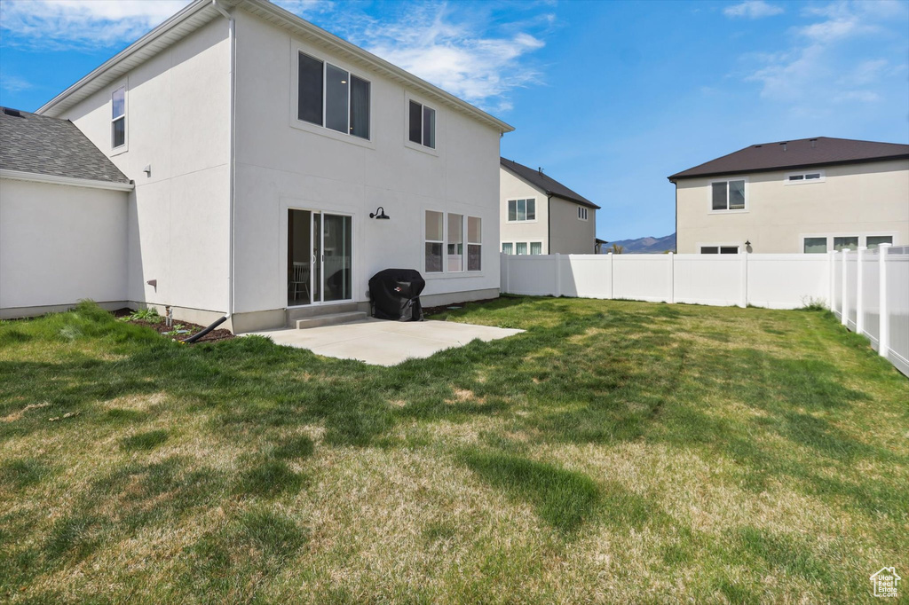 Back of property with a yard, a patio, fence, and stucco siding
