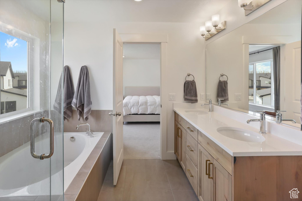 Ensuite bathroom featuring double vanity, a sink, and a healthy amount of sunlight