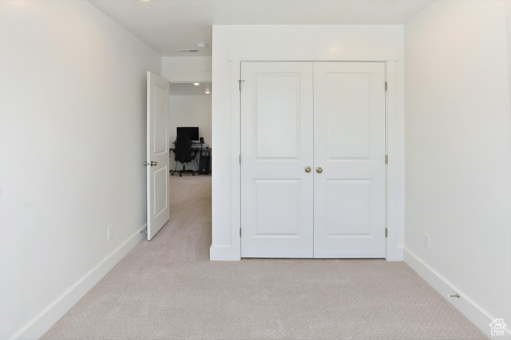 Unfurnished bedroom with baseboards, a closet, and light carpet