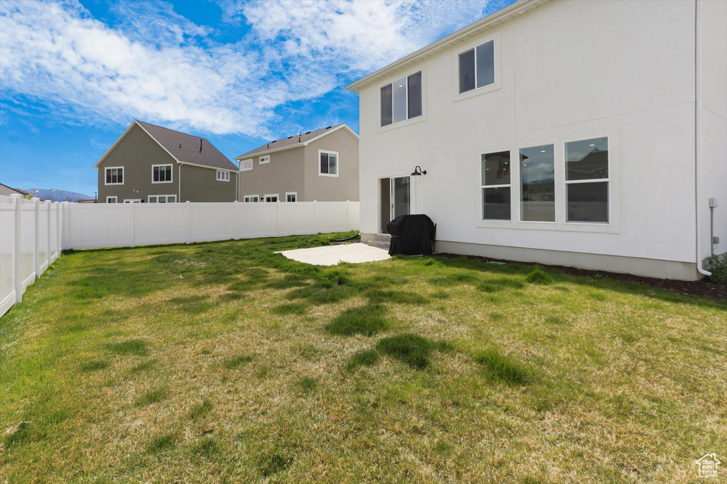 Rear view of property featuring a lawn, a fenced backyard, stucco siding, and a patio