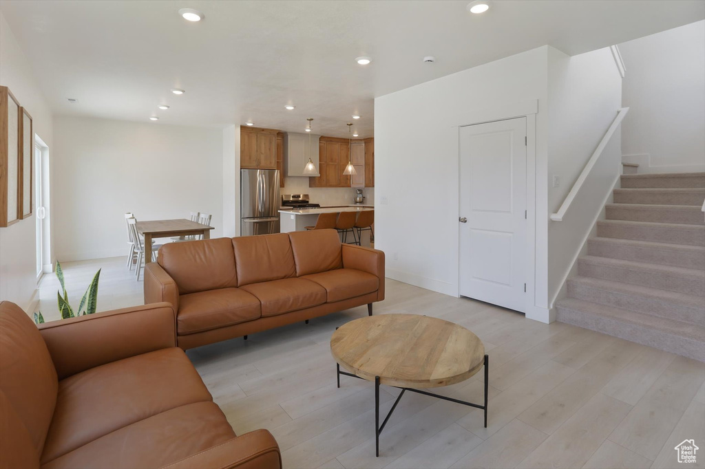 Living area with light wood-style floors, baseboards, recessed lighting, and stairs