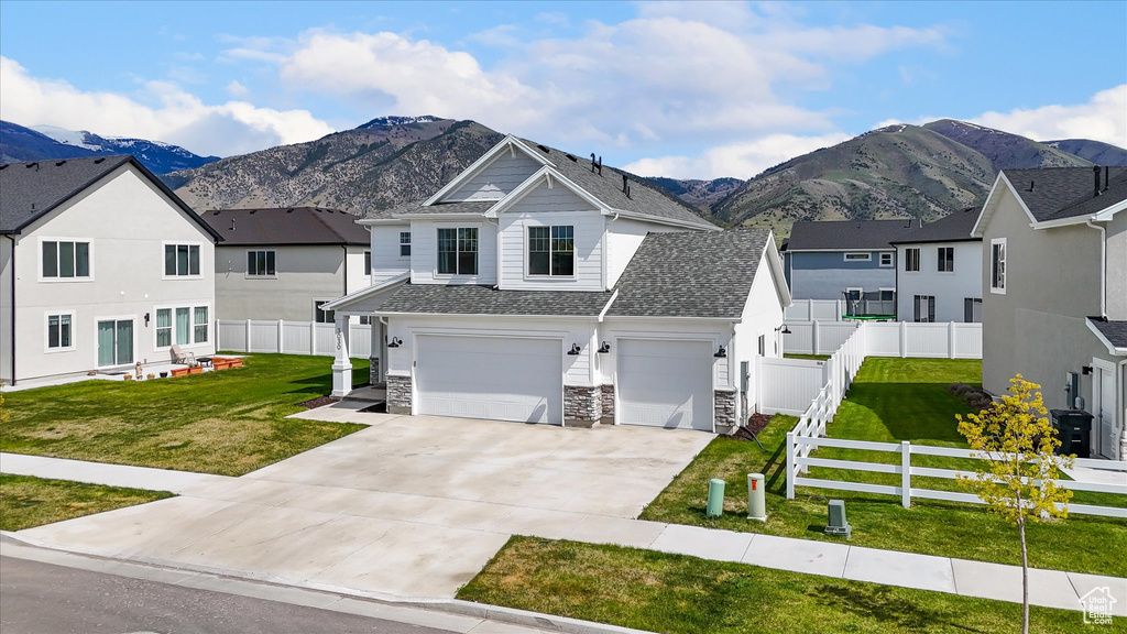 View of front of home featuring a mountain view, concrete driveway, and a front yard