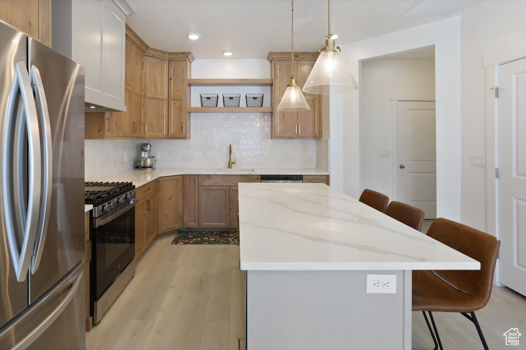 Kitchen with backsplash, a kitchen bar, a center island, a sink, and stainless steel appliances