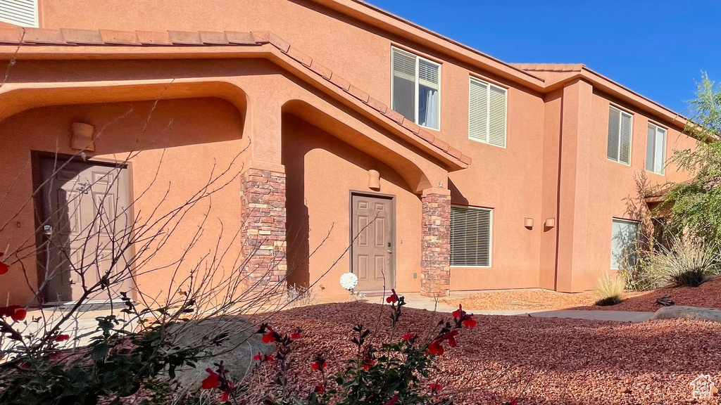 Doorway to property with stucco siding, a tile roof, and stone siding