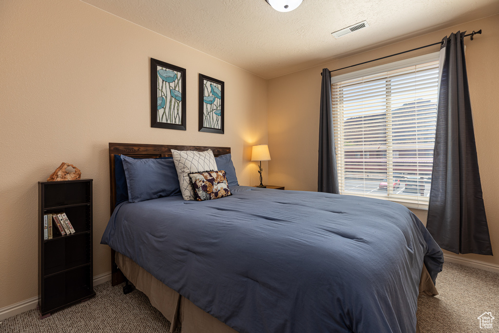 Bedroom featuring carpet flooring, baseboards, and a textured ceiling