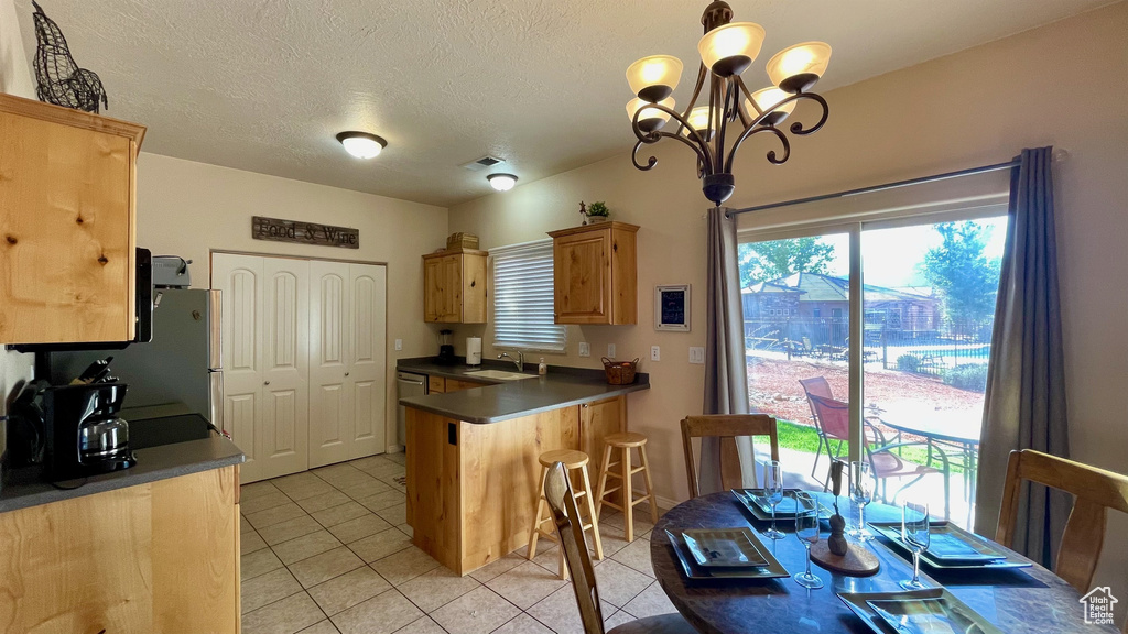 Kitchen with an inviting chandelier, visible vents, light brown cabinets, dark countertops, and light tile patterned floors