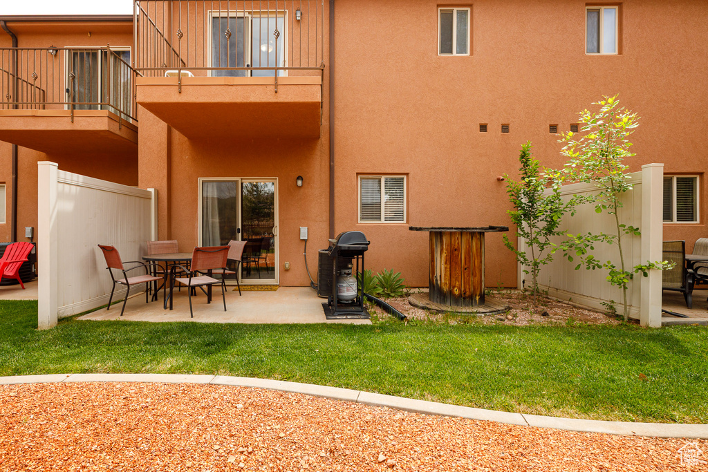 Rear view of house with a balcony, stucco siding, and a patio