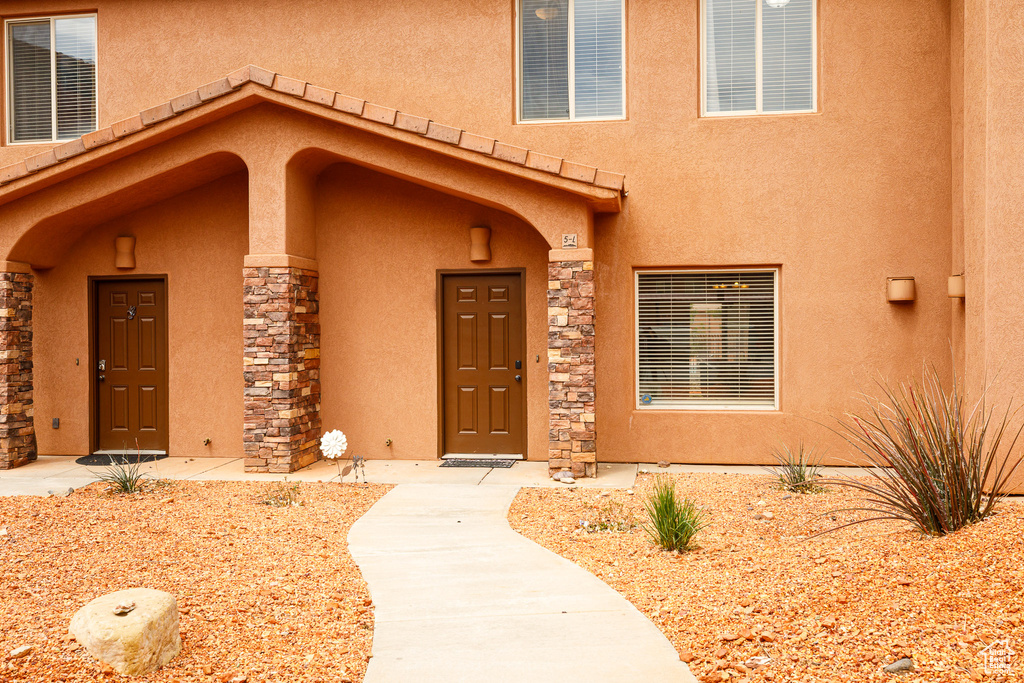 View of exterior entry with stucco siding and stone siding
