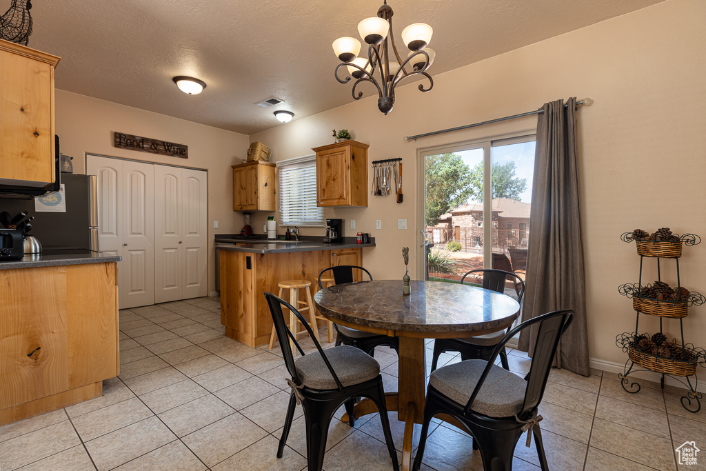 Dining space with light tile patterned flooring, a chandelier, and baseboards