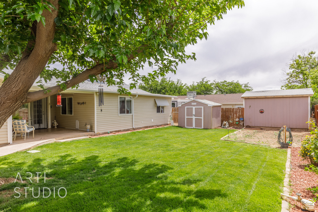 View of yard with fence, an outbuilding, a patio area, and a storage unit