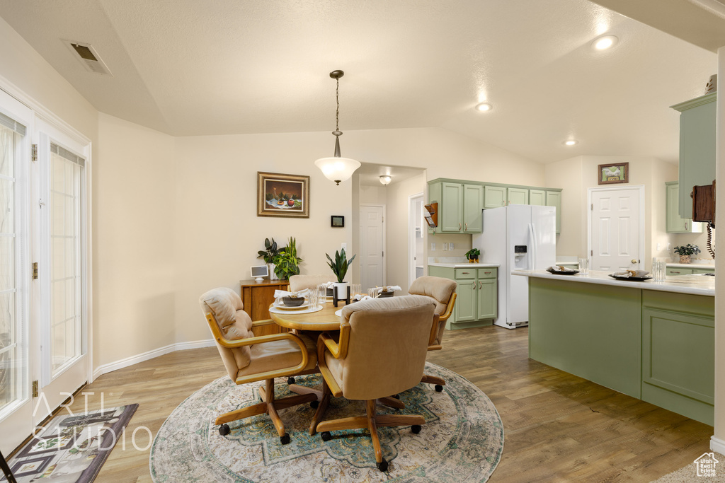 Dining space featuring baseboards, visible vents, lofted ceiling, and light wood-style floors