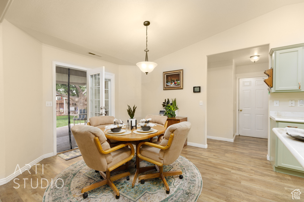 Dining space featuring baseboards, light wood-style flooring, vaulted ceiling, and visible vents