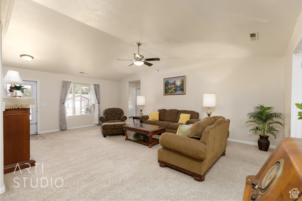 Carpeted living room featuring a ceiling fan, baseboards, visible vents, and lofted ceiling