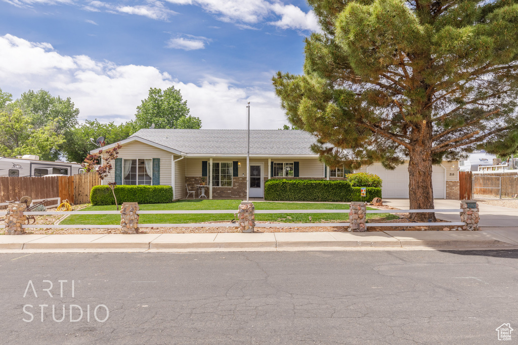 Ranch-style home featuring an attached garage, a front lawn, fence, and driveway