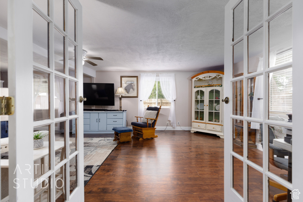 Living room with a textured ceiling, dark wood finished floors, french doors, a ceiling fan, and baseboards