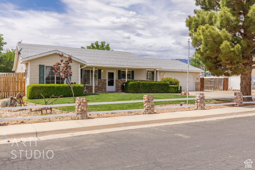 Ranch-style home with fence, an attached garage, a front yard, concrete driveway, and covered porch