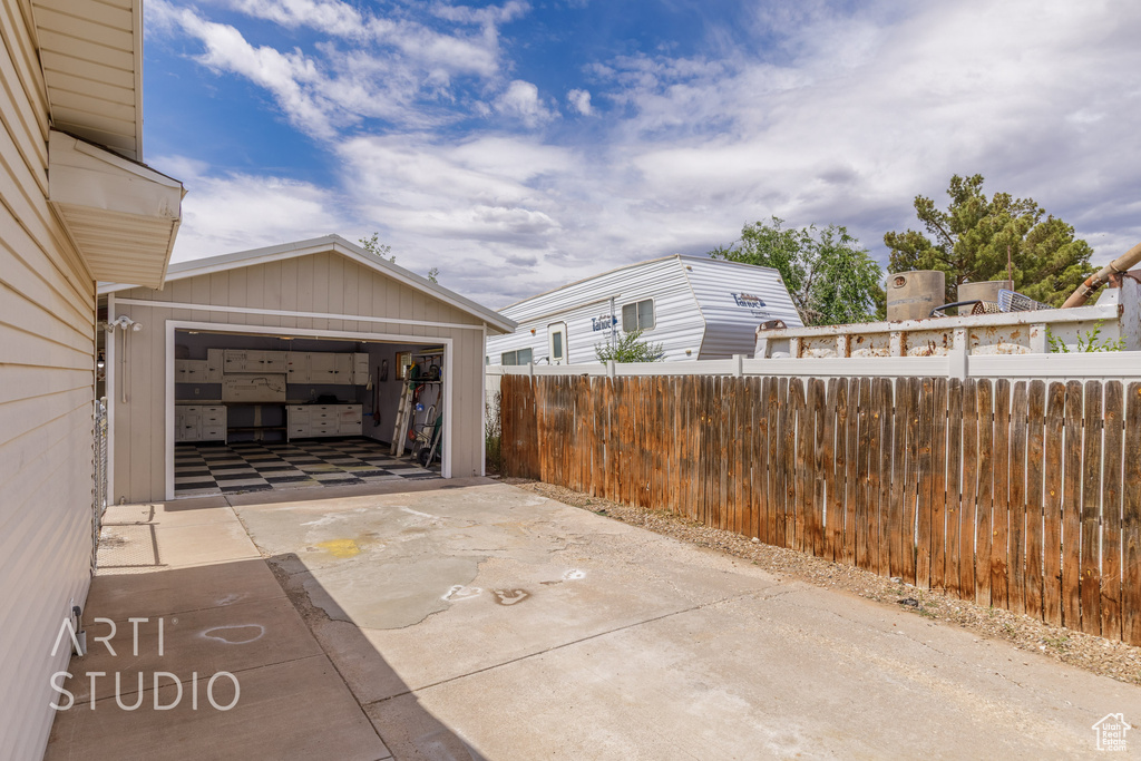 View of patio featuring fence and concrete driveway