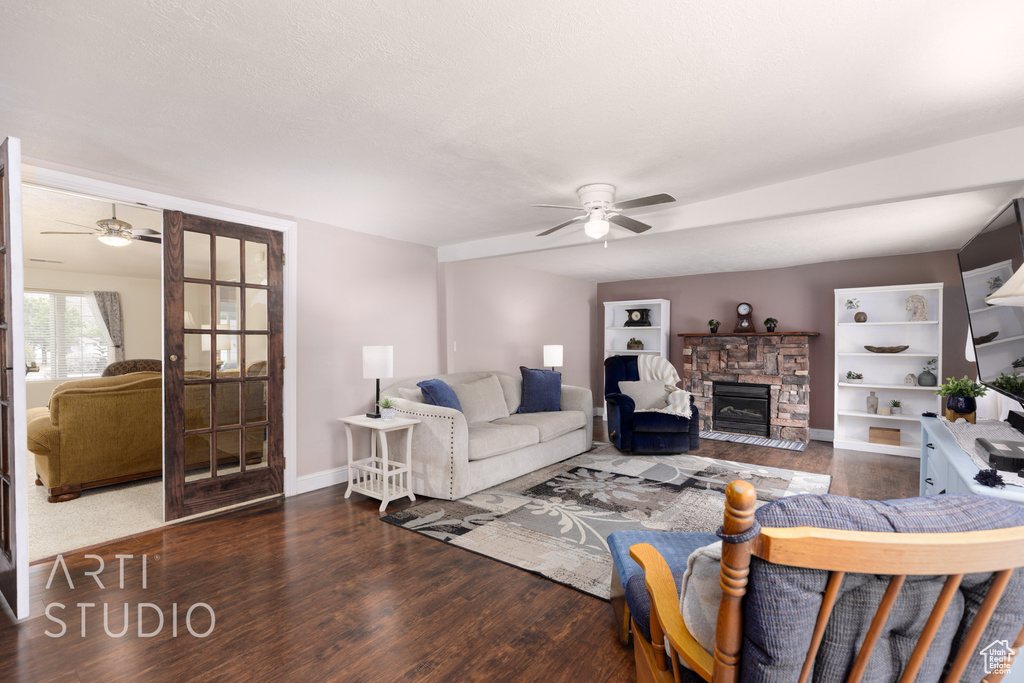 Living room with a ceiling fan, baseboards, wood finished floors, and a fireplace