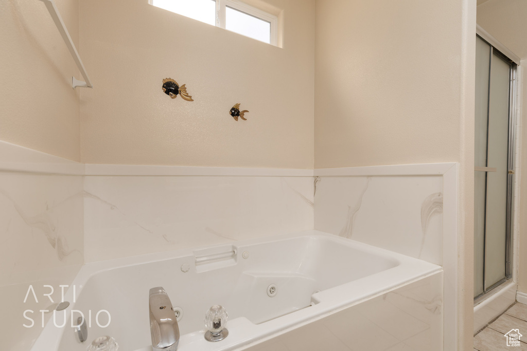 Full bath featuring tile patterned floors, a tub with jets, and a stall shower