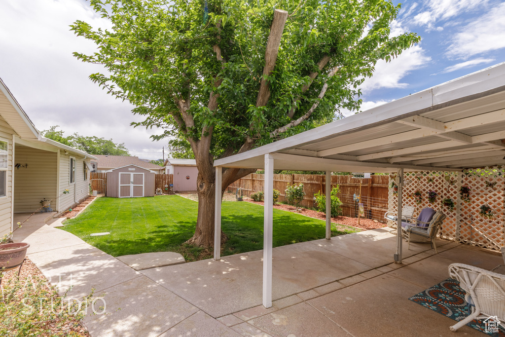 View of patio featuring a storage unit, a fenced backyard, and an outdoor structure