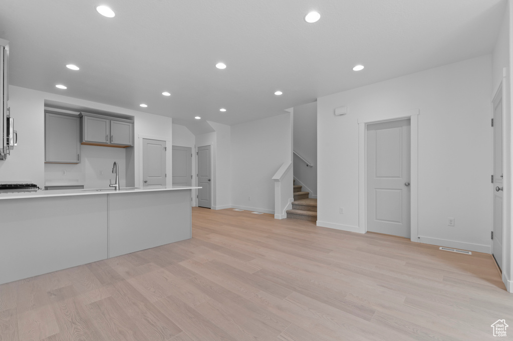 Kitchen with a sink, light countertops, gray cabinets, and recessed lighting