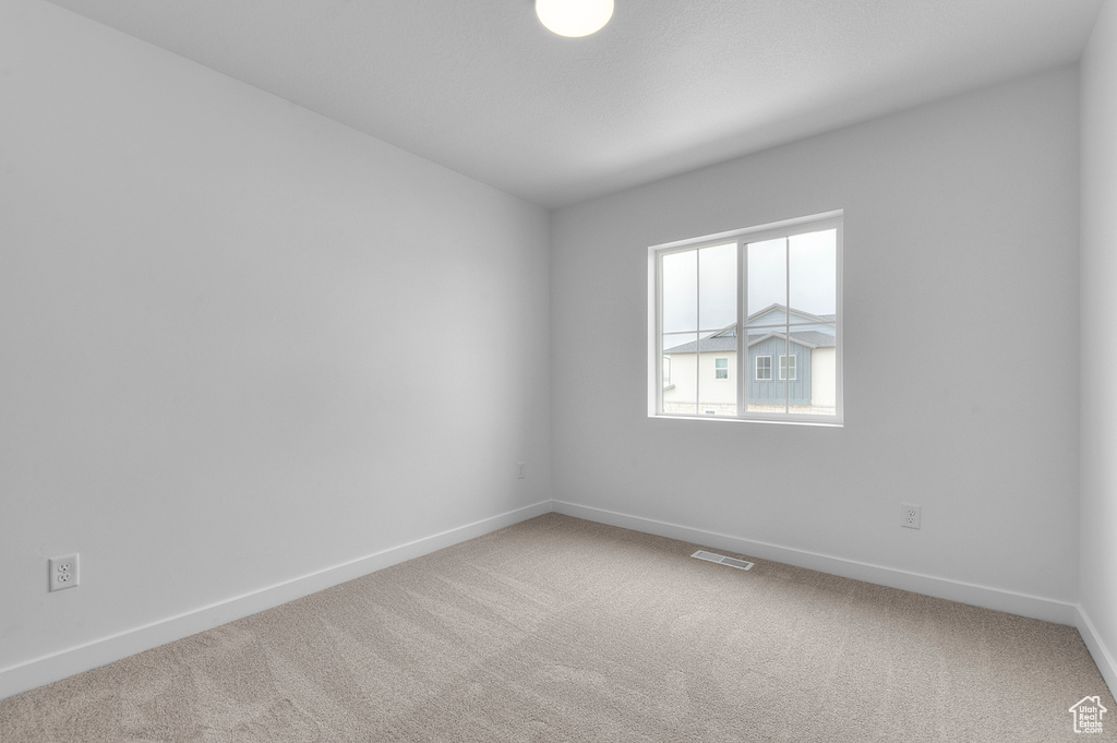 Carpeted empty room with visible vents and baseboards
