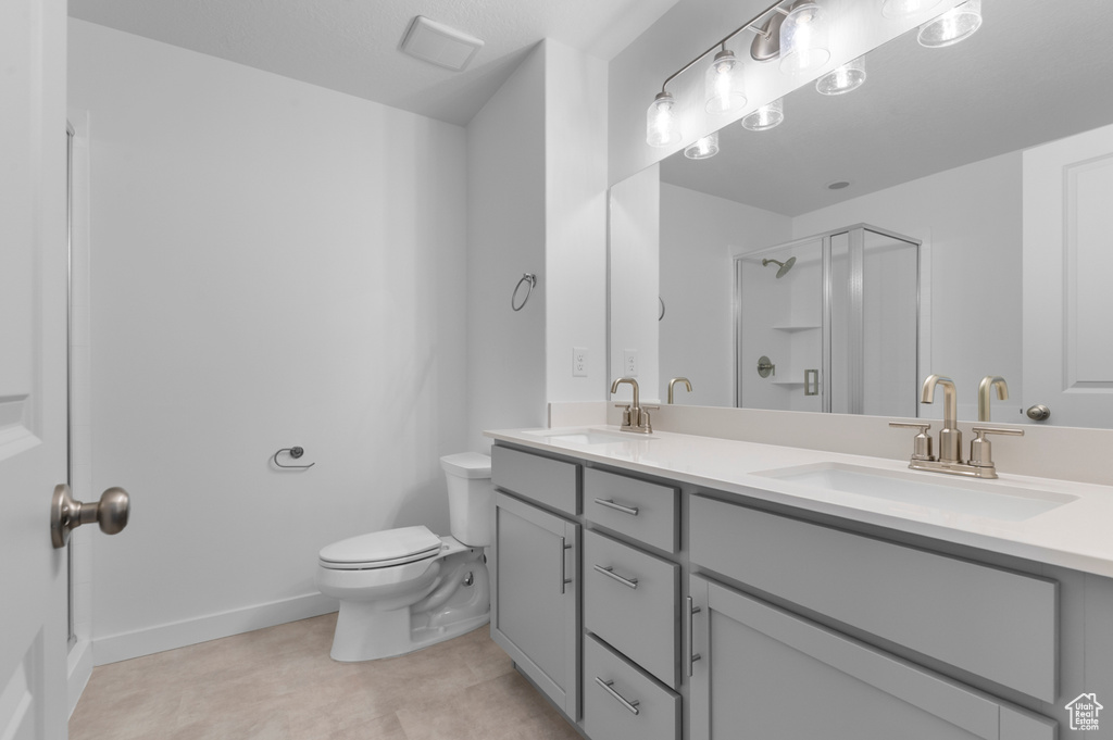 Bathroom featuring double vanity, a sink, toilet, and a shower stall