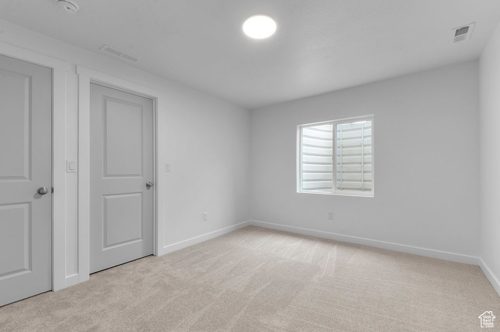 Interior space featuring baseboards, light carpet, and visible vents