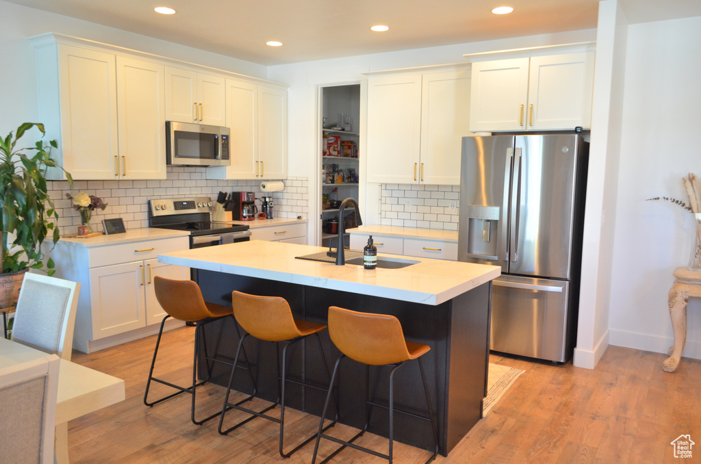 Kitchen with light wood-type flooring, a sink, appliances with stainless steel finishes, and recessed lighting