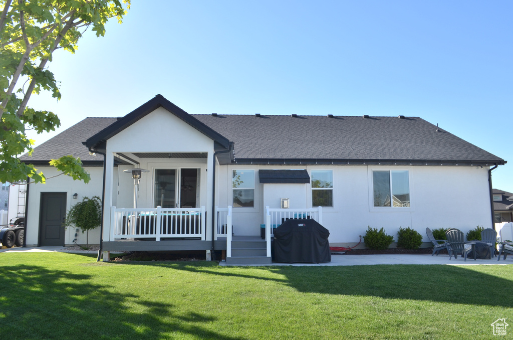View of front of home featuring roof with shingles, a patio, stucco siding, and a front yard