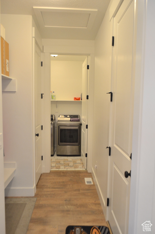 Hallway with washer and dryer, visible vents, attic access, and light wood-type flooring
