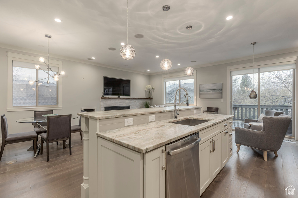 Kitchen featuring stainless steel dishwasher, a sink, a kitchen island with sink, and hardwood / wood-style flooring