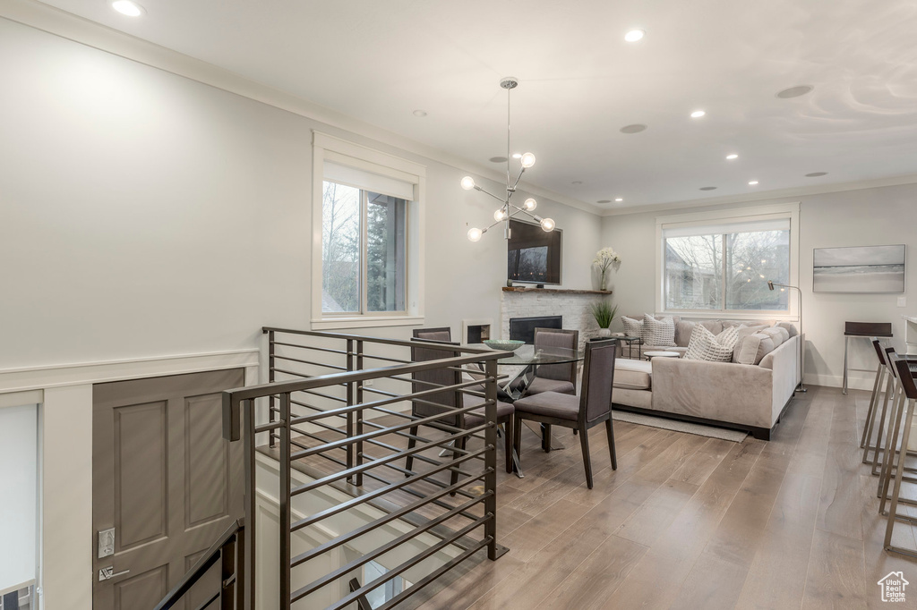Dining room featuring recessed lighting, ornamental molding, light wood-style flooring, and a fireplace