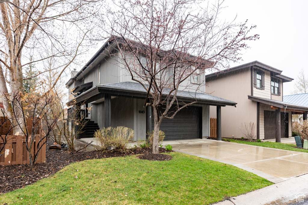 View of front facade featuring a front lawn, metal roof, and concrete driveway