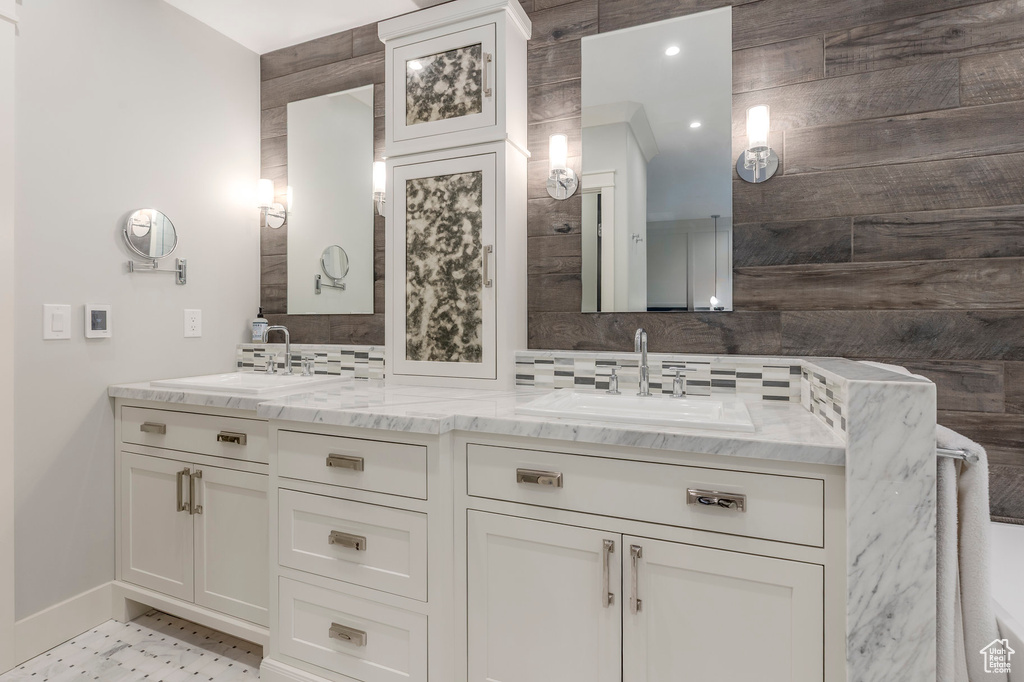 Bathroom with a sink, baseboards, backsplash, and double vanity