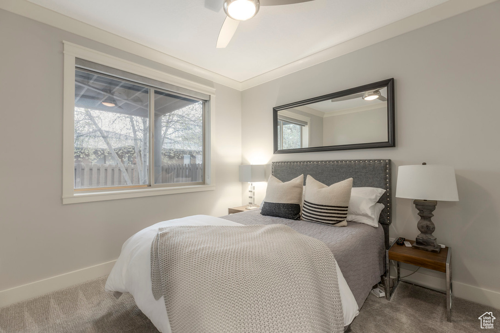 Carpeted bedroom with baseboards, ornamental molding, and a ceiling fan