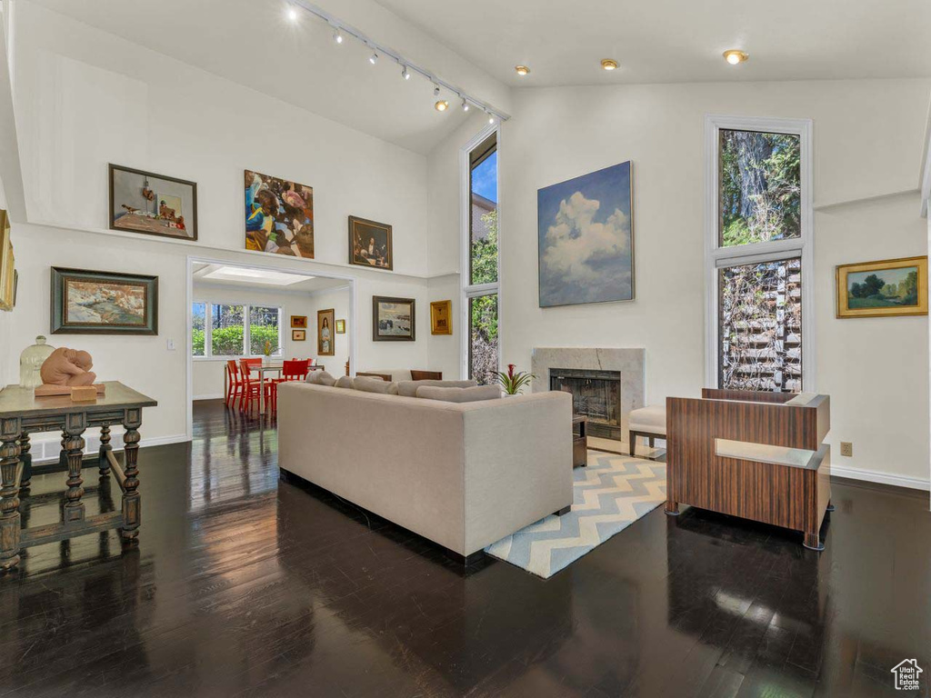 Living room featuring wood finished floors, high vaulted ceiling, baseboards, and a high end fireplace