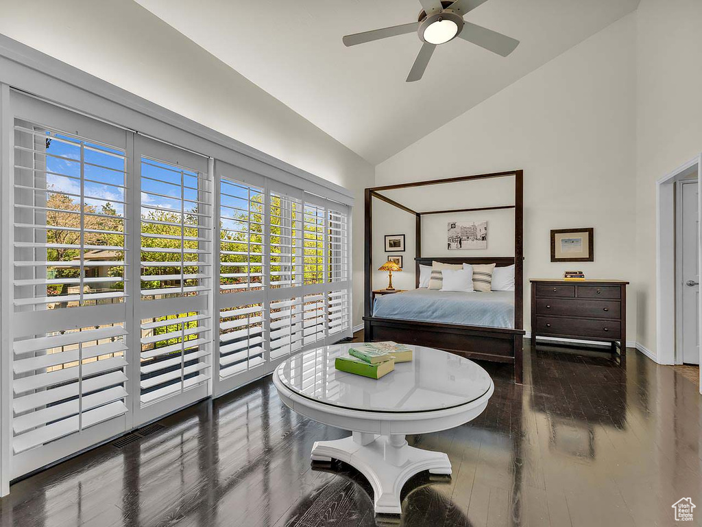 Bedroom with high vaulted ceiling, multiple windows, baseboards, and wood finished floors