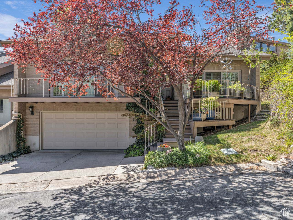 Obstructed view of property with an attached garage, concrete driveway, stairway, and brick siding