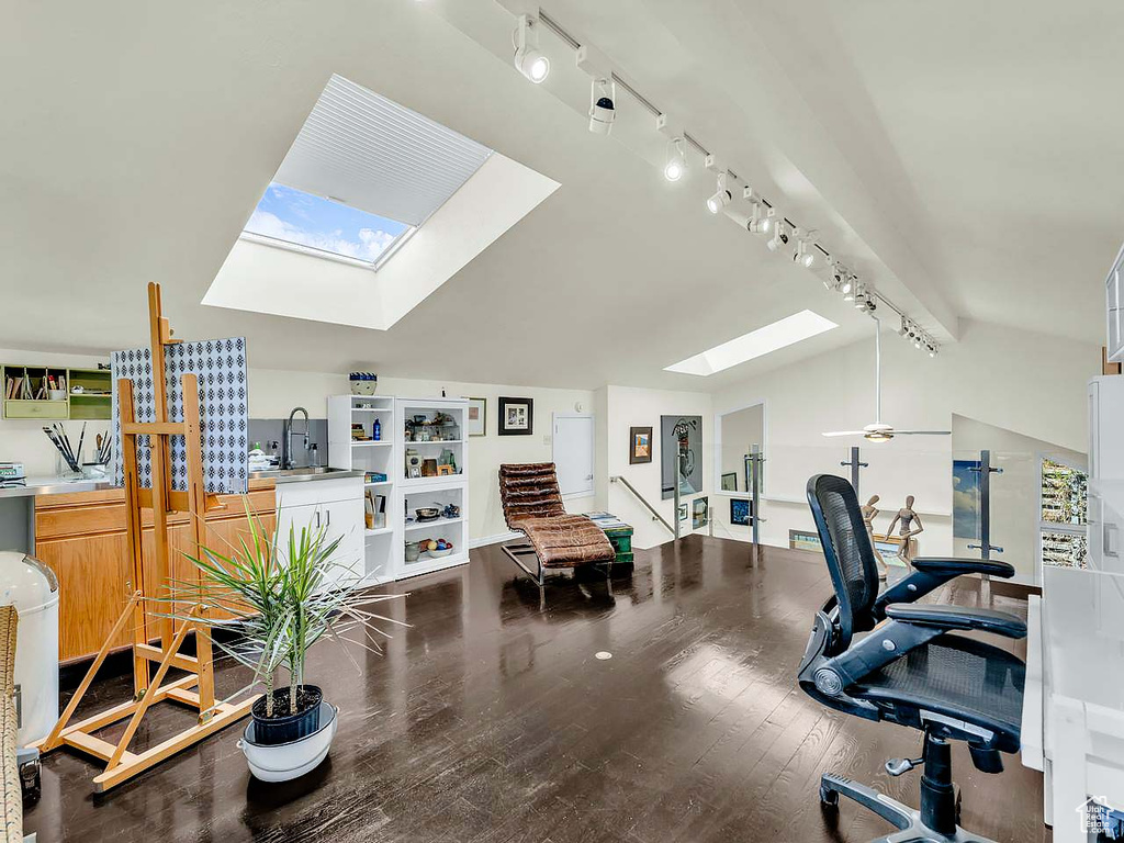 Office space with rail lighting, a sink, wood finished floors, and vaulted ceiling with skylight