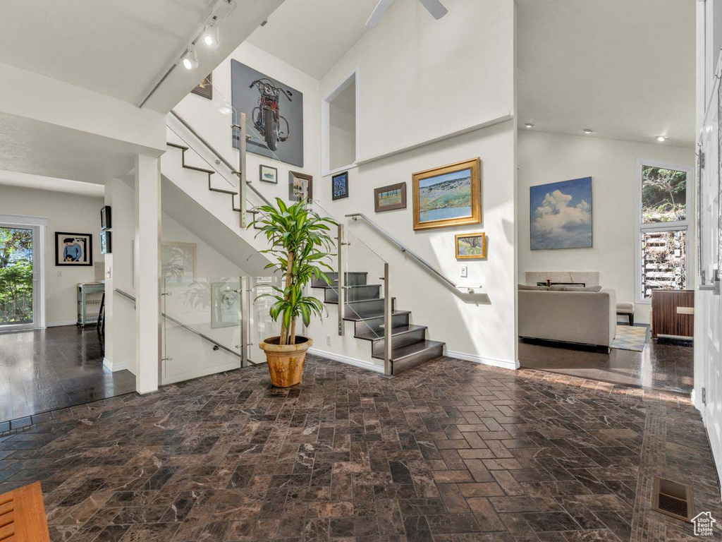 Stairs with visible vents, rail lighting, baseboards, and a high ceiling