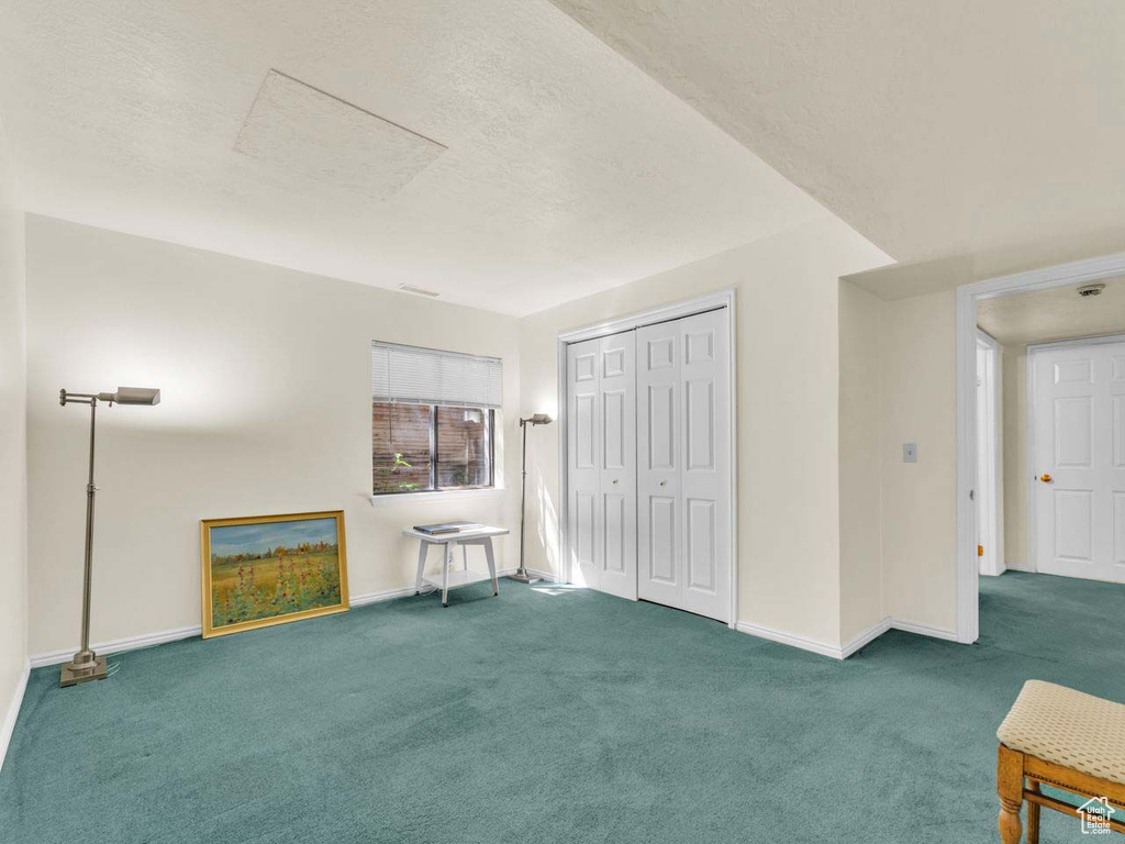 Interior space with carpet floors, baseboards, and a textured ceiling