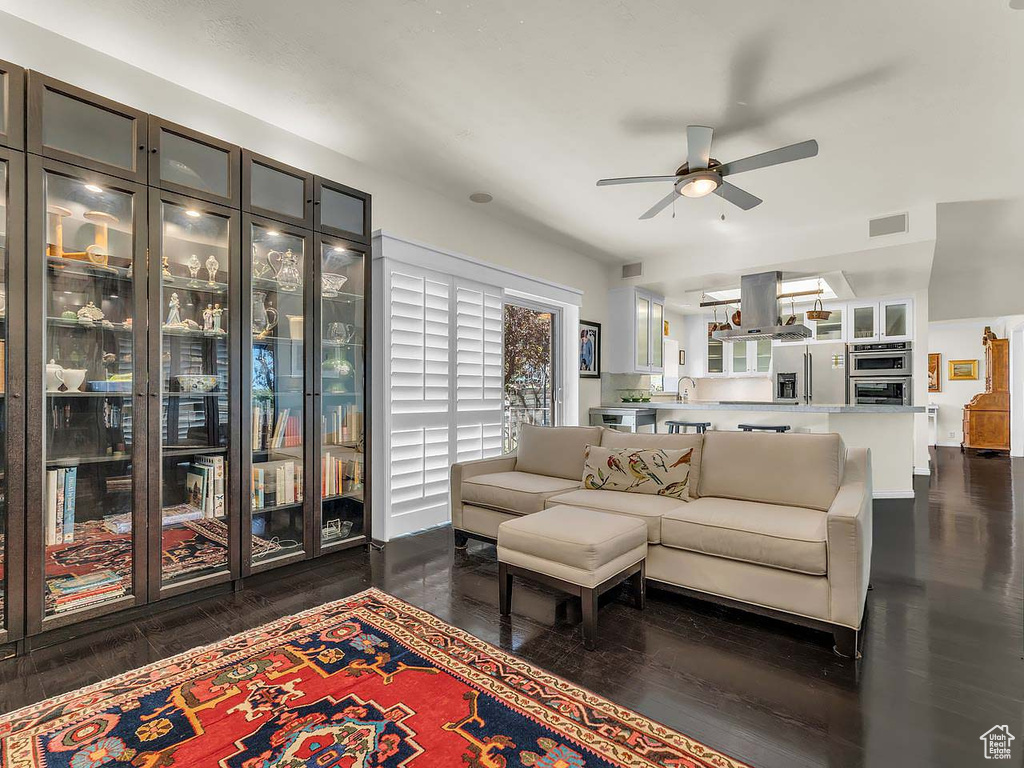 Living room with ceiling fan, visible vents, and dark wood-type flooring
