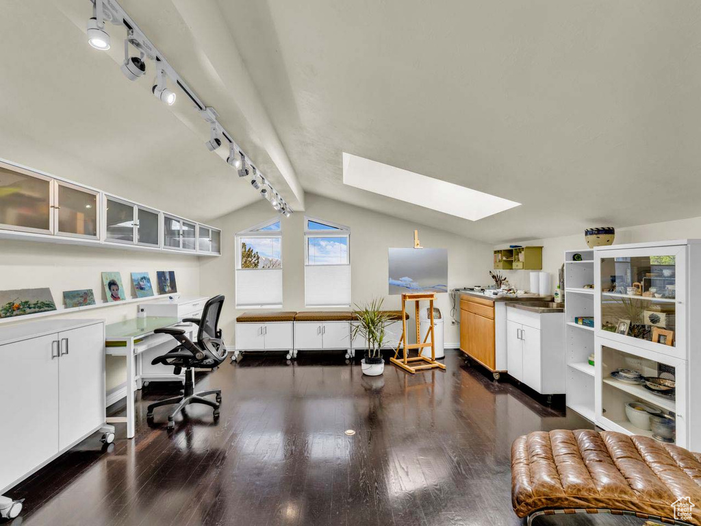 Office with rail lighting, lofted ceiling with skylight, and dark wood-style floors